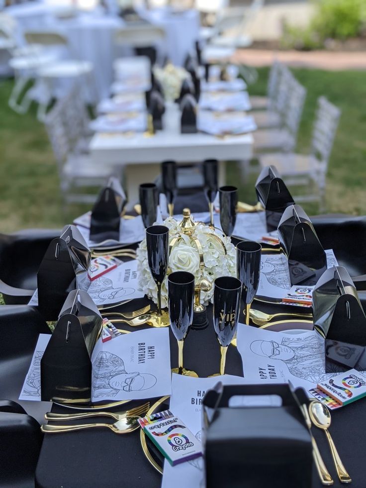 the table is set with black and gold place settings