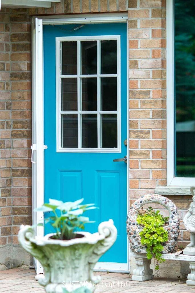 a blue front door with two chairs and a potted plant in the foreground