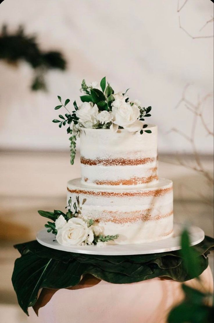 a wedding cake with white flowers and greenery on top