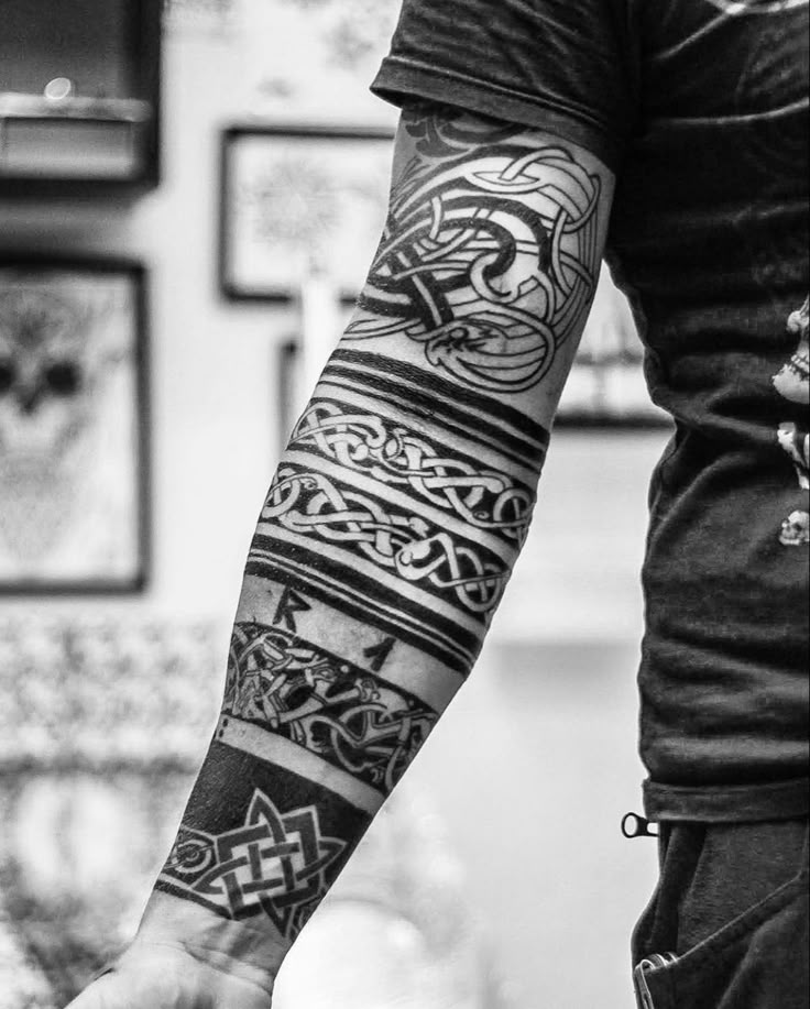 black and white photo of a man's arm with celtic tattoos on his arms