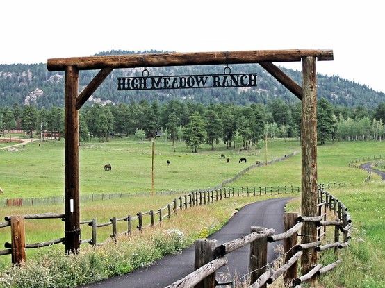 a wooden sign that reads high meadow ranch on the side of a road in front of a lush green field