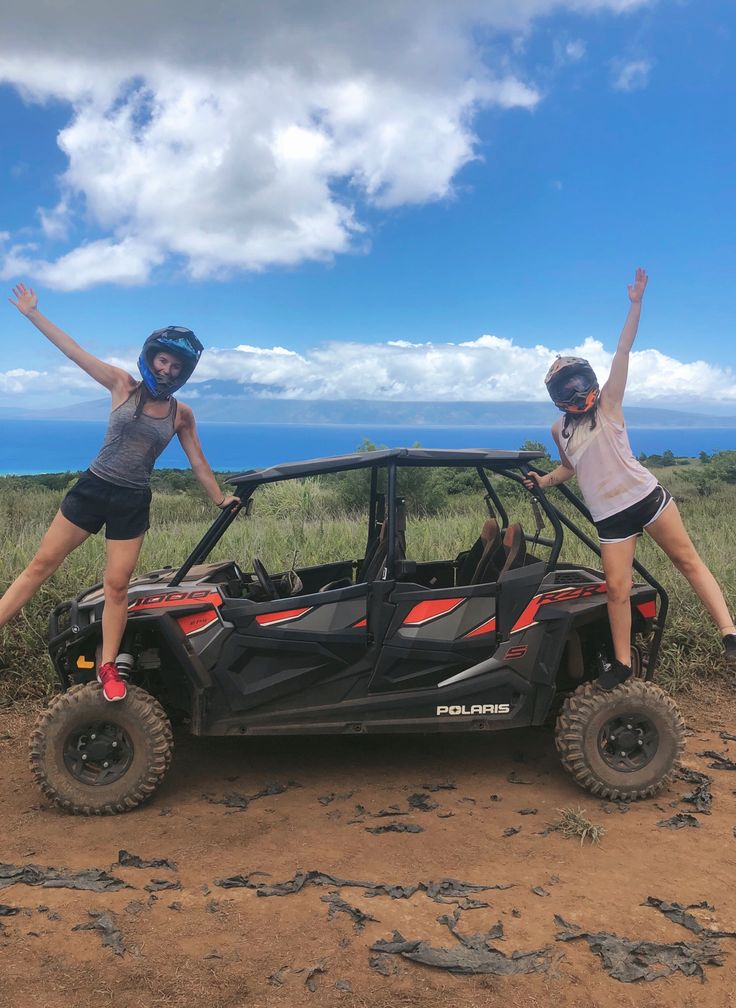 two girls are jumping on the roof of a four - doored vehicle