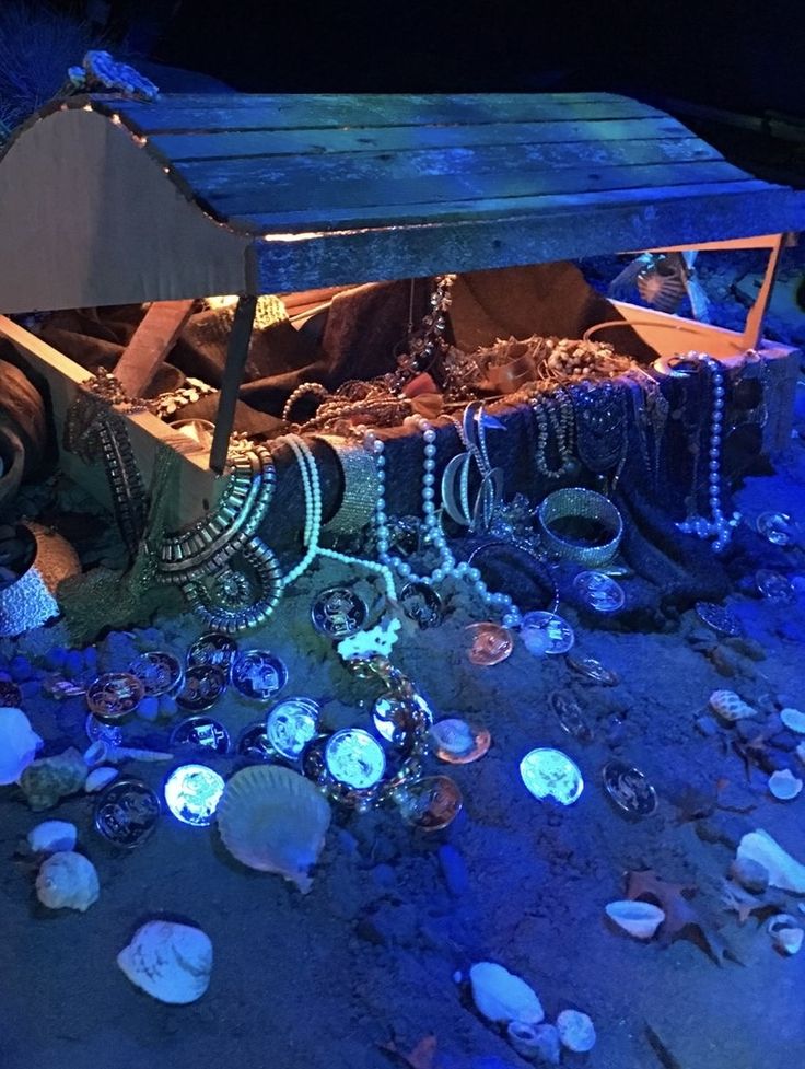 an old wooden box with many necklaces on the ground in front of some shells