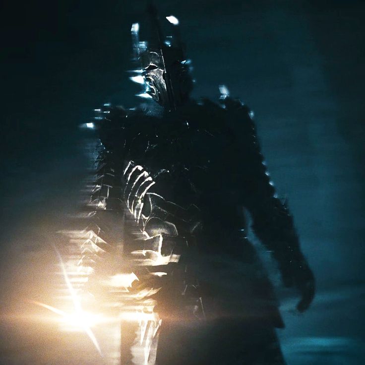 a man in armor walking through the dark with light coming from his face and hands