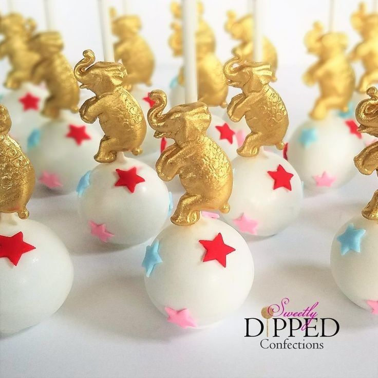 cake pops decorated with gold and red stars on top of white frosted balls in the shape of elephants