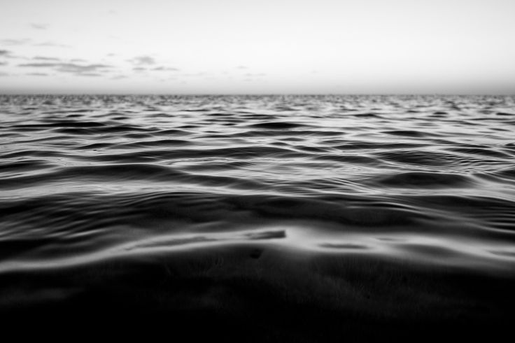 black and white photo of the ocean at sunset