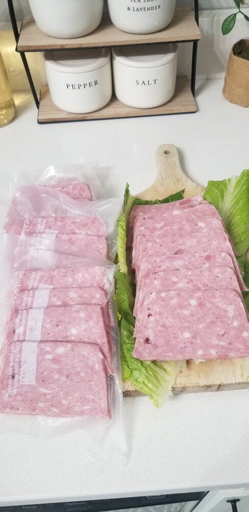 two sandwiches with lettuce wrapped in plastic wrap sitting on top of a counter