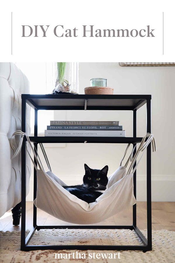 a black cat laying in a hammock on top of a table