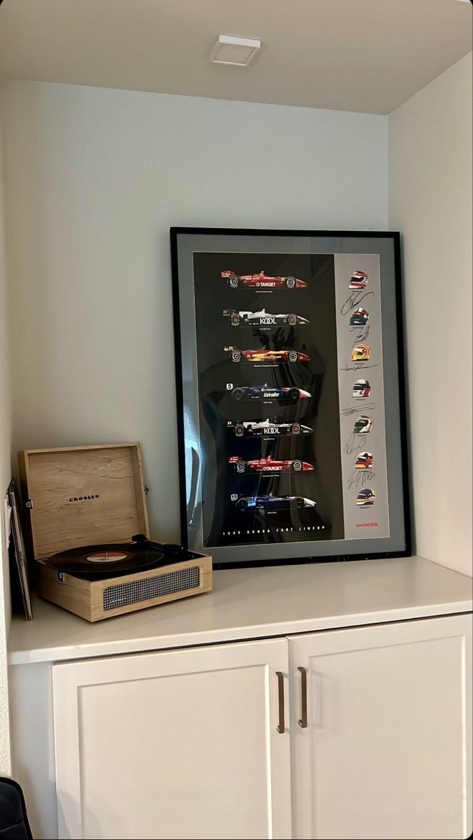 an old record player sitting on top of a white cabinet next to a framed poster