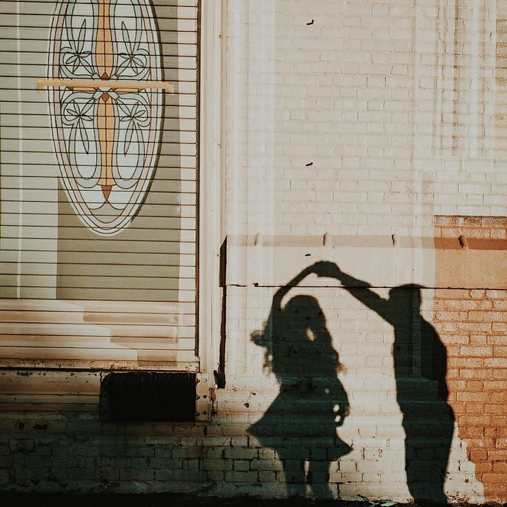 the shadow of a person standing in front of a building with a cross on it