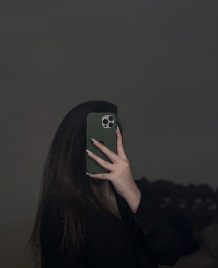 a woman holding up her phone to take a selfie in front of the camera