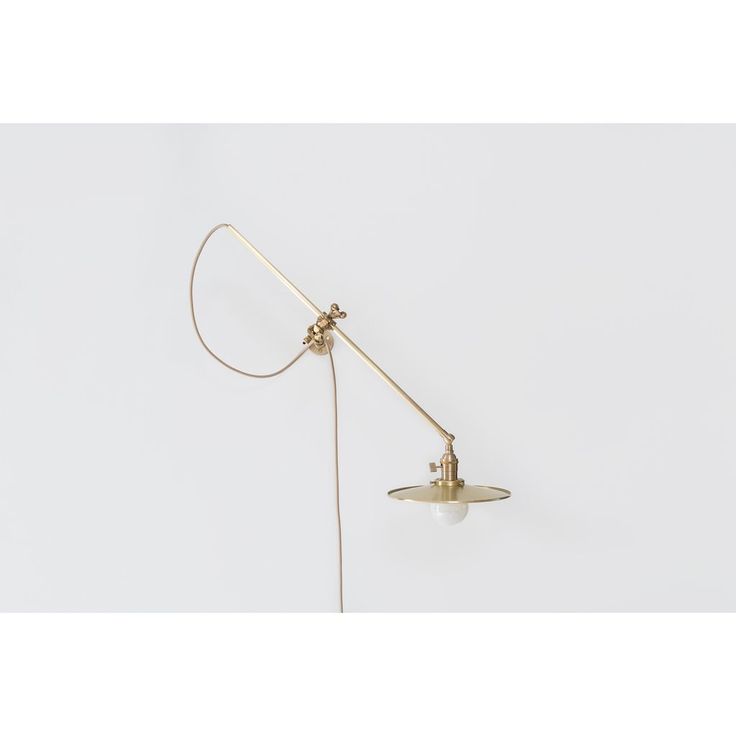 an old fashioned desk lamp on a white wall with a cord attached to the arm