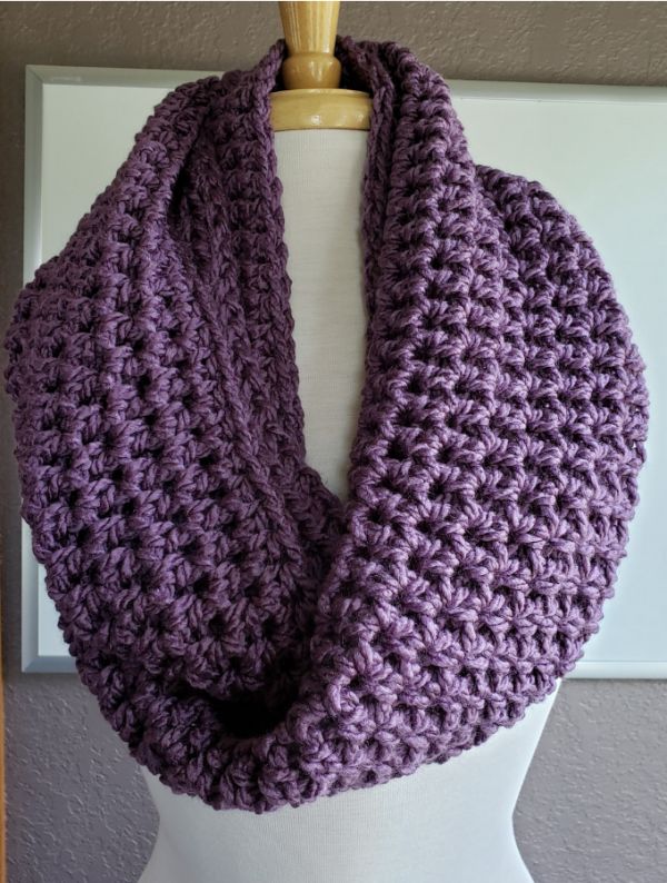 a purple crocheted scarf is on a mannequin