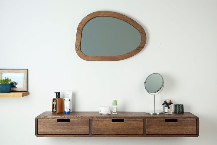 a wooden shelf with two drawers and a mirror on the wall next to each other