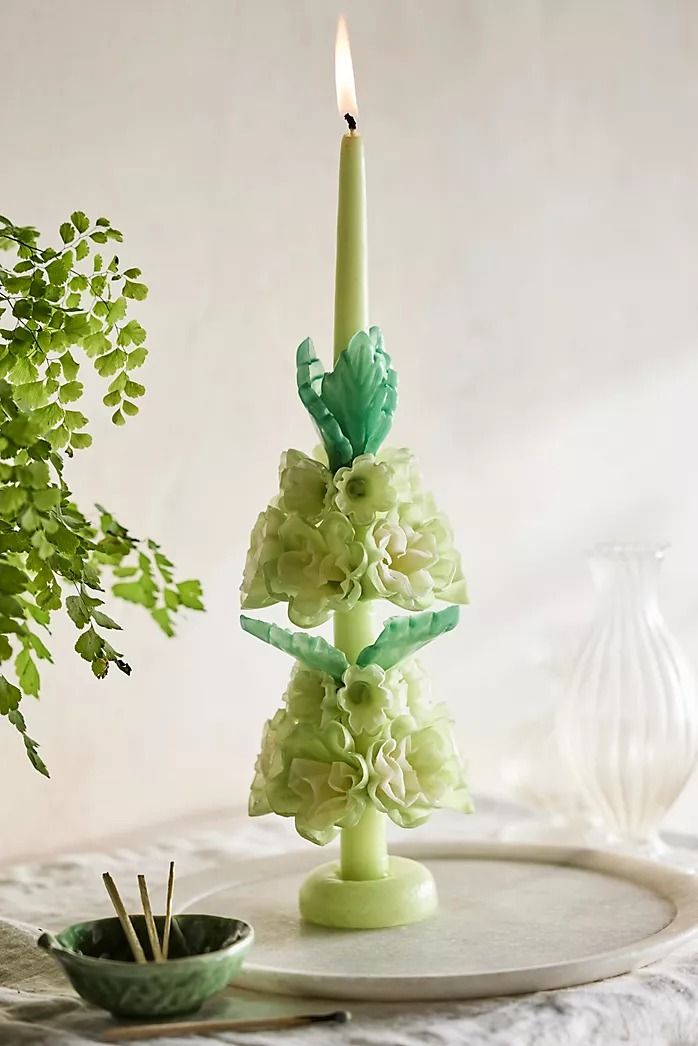 a candle that is on top of a plate next to a potted plant and bowl