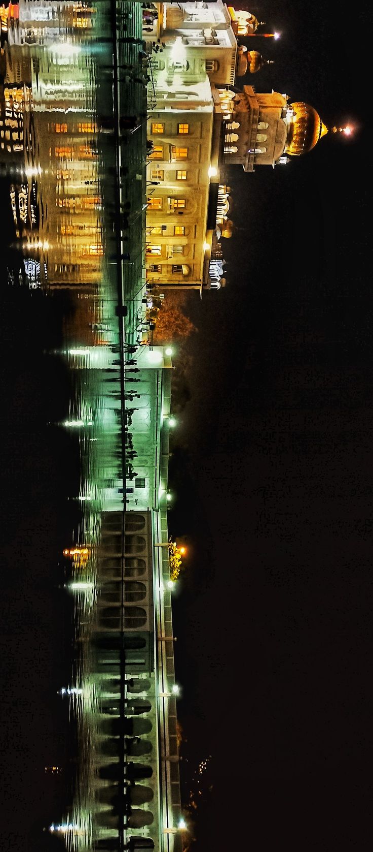 an aerial view of a city at night with buildings lit up in green and yellow