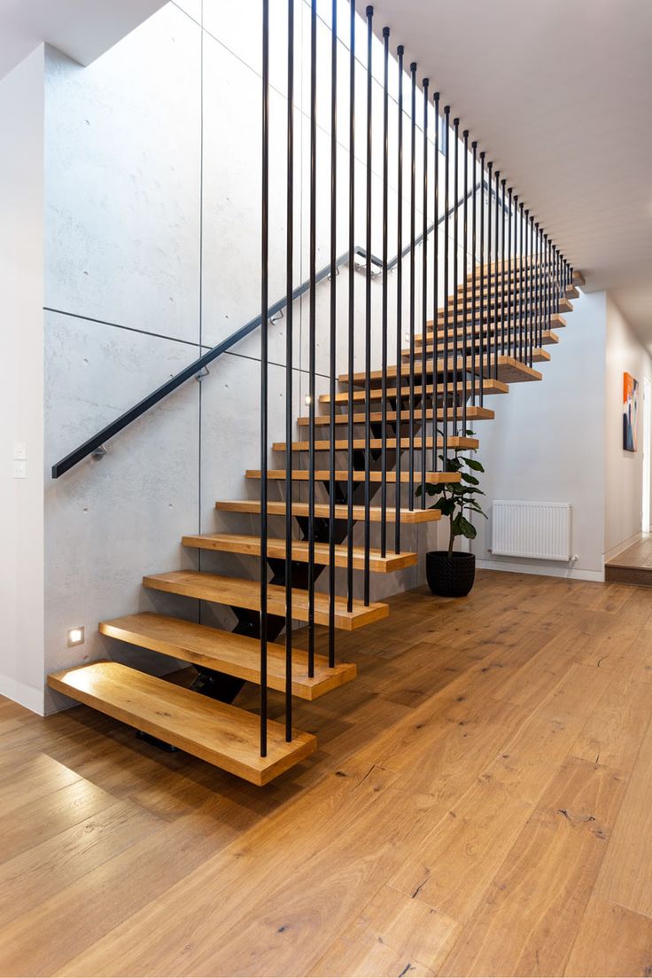 a wooden staircase with metal handrails next to a potted plant on the floor