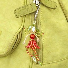 a green purse with a red and white beaded doll hanging from it's side