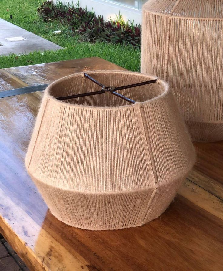 two lamps sitting on top of a wooden table next to each other in front of a house