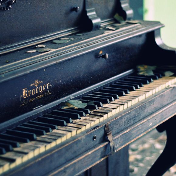 an old black piano is sitting in the room