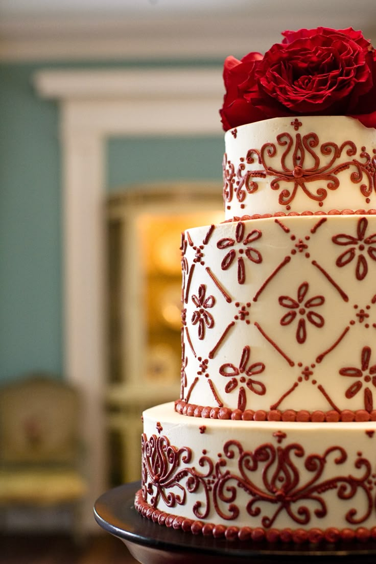 a three tiered cake with red flowers on top