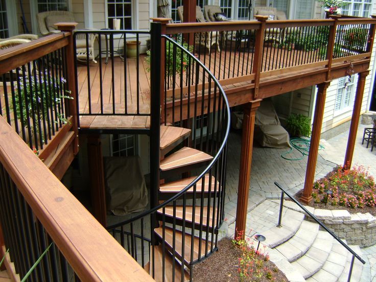 a spiral staircase in the middle of a patio with steps leading up to an upper level