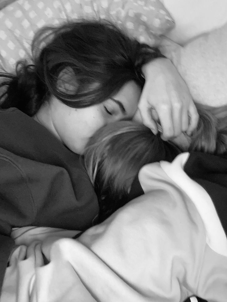 a woman laying on top of a bed next to a little boy under a blanket