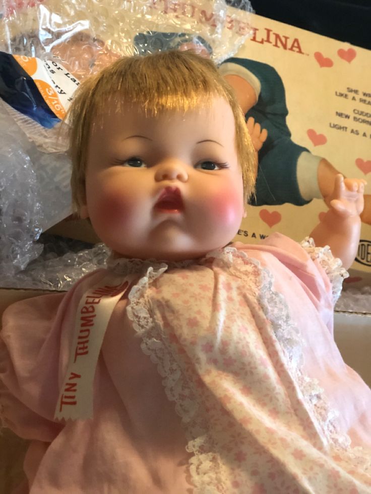 a baby doll with blonde hair wearing a pink dress