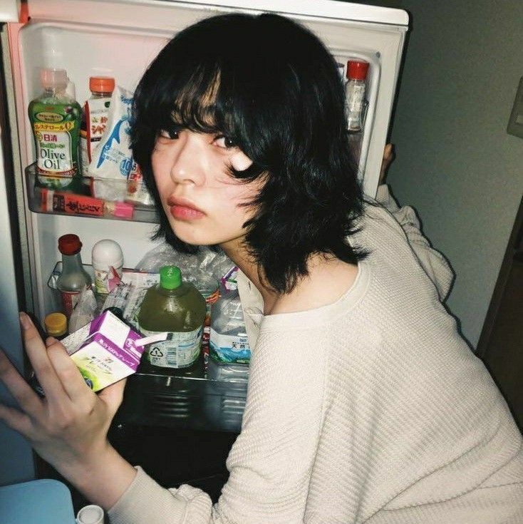 a woman is looking in the refrigerator with her hand on an empty carton,