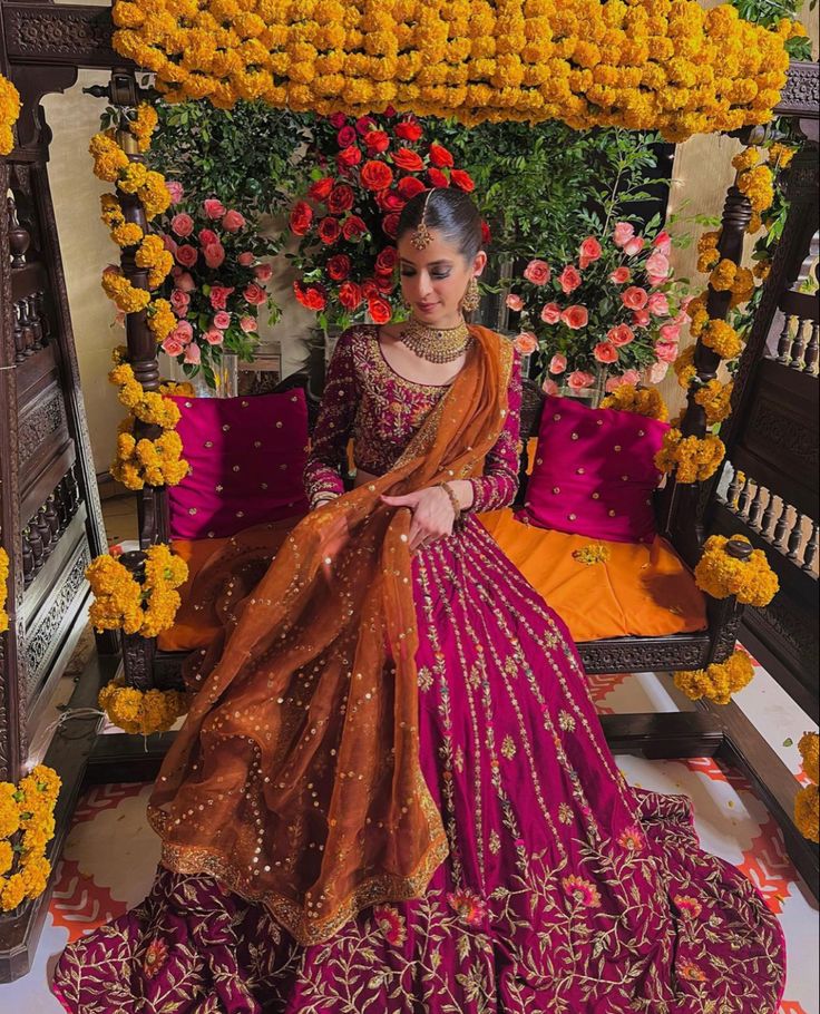 a woman sitting on top of a bed in a purple and orange dress with flowers