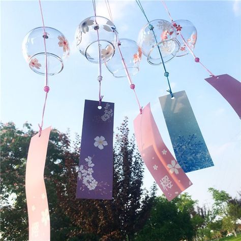 some glass balls hanging from a string in the air with ribbons attached to them and flowers on them