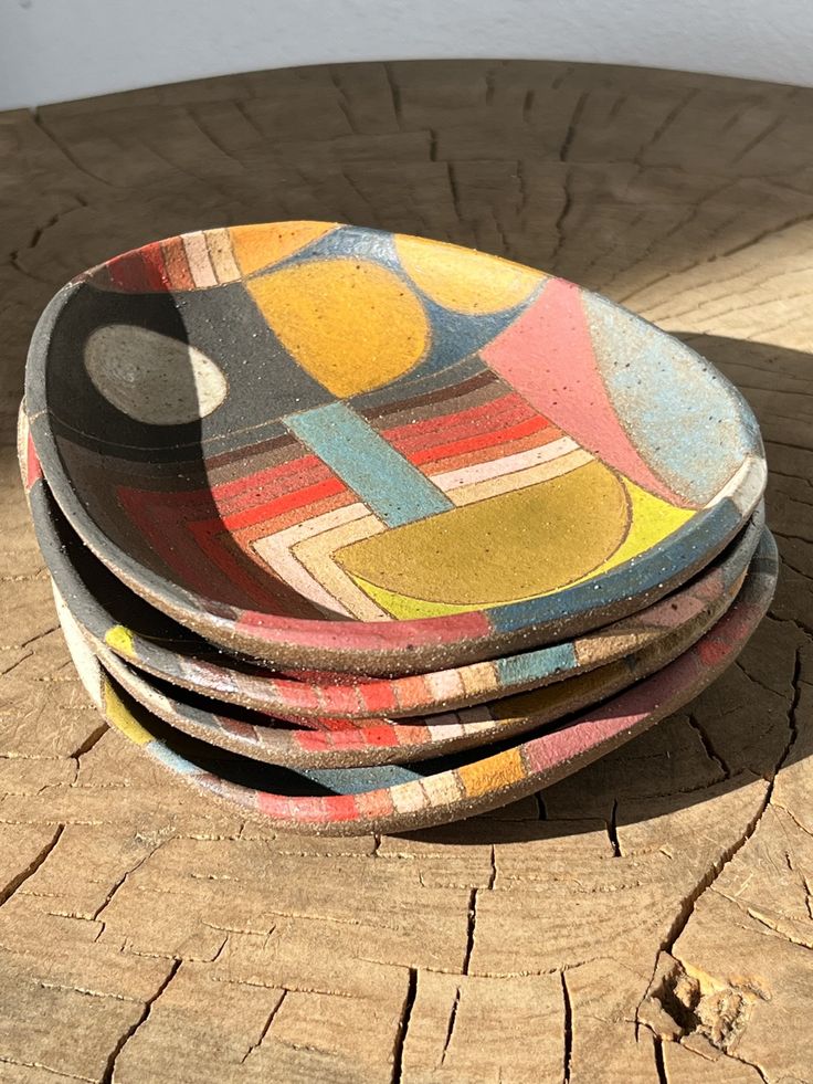 a stack of colorful plates sitting on top of a wooden table next to each other