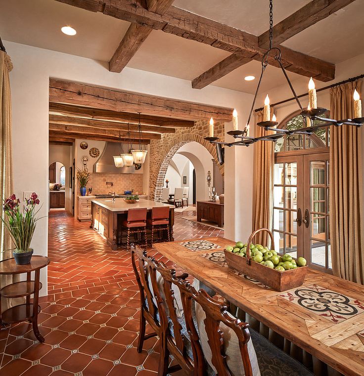 a dining room table and chairs in front of a kitchen with an arched doorway that leads to the outside