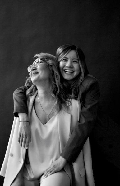 black and white photograph of two women sitting next to each other with their arms around one another