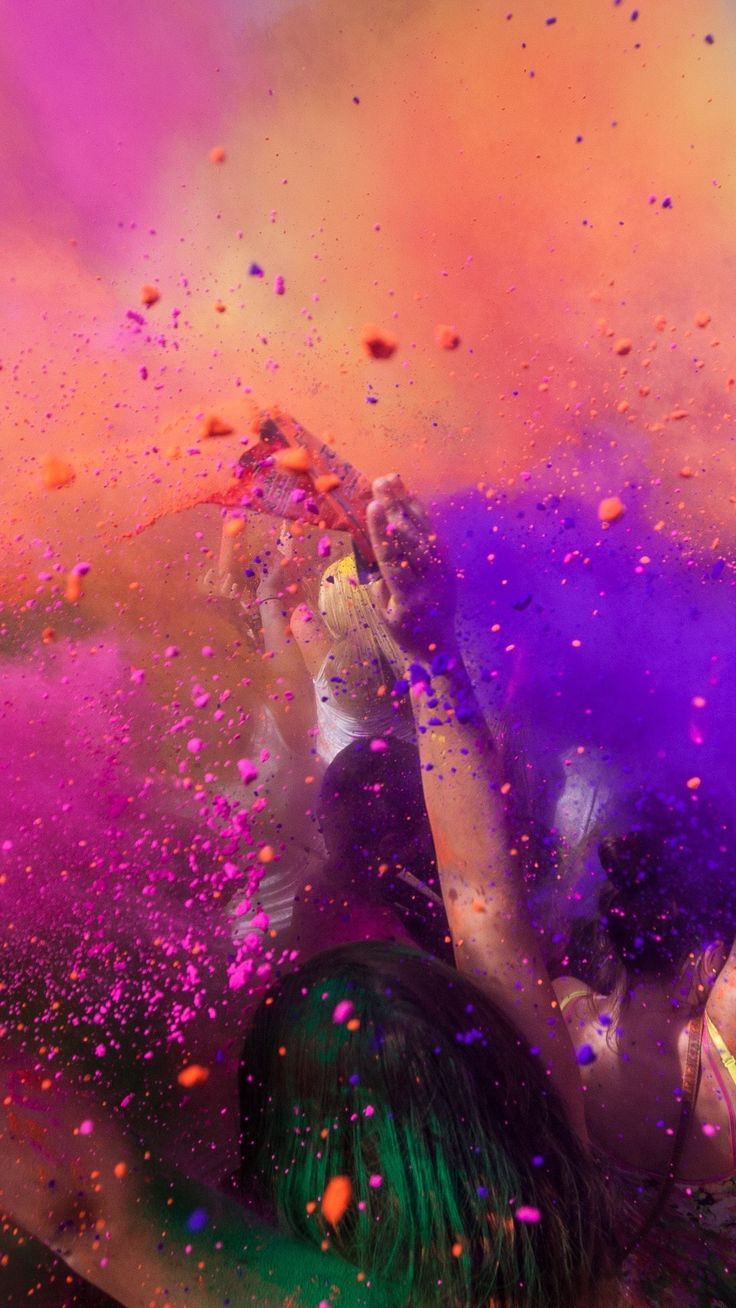 two people are covered in colored powder and confetti