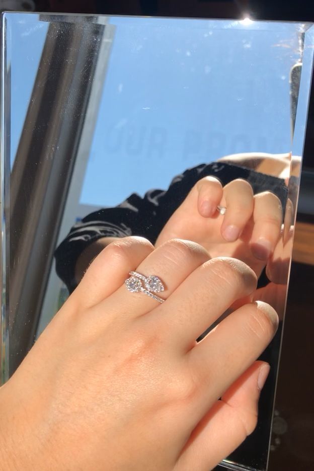 a woman's hand with a ring on her finger, in front of a mirror