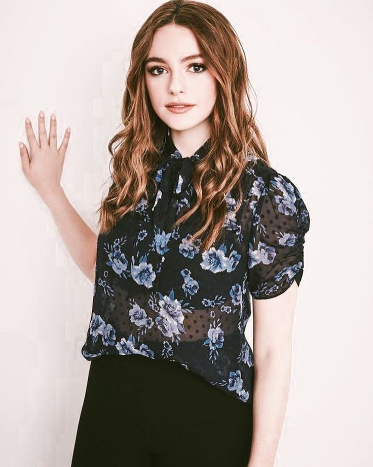 a woman with long hair wearing a black and blue shirt is posing for the camera