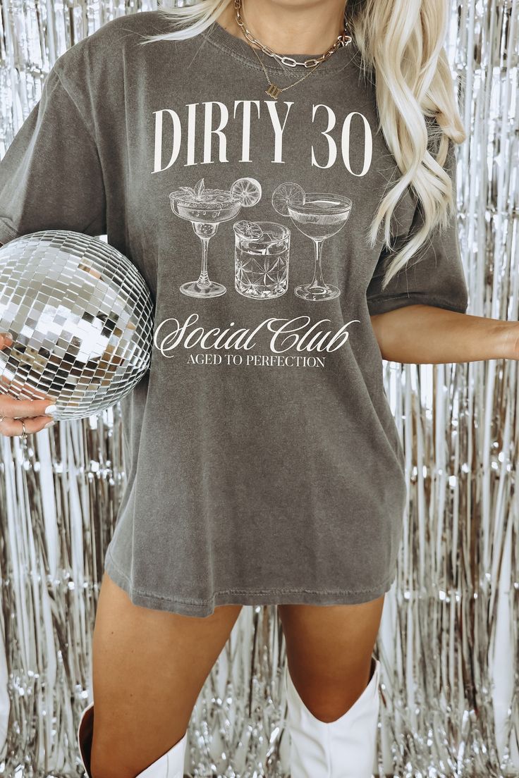 a woman holding a disco ball in front of a tin foil backdrop with the words dirty 30 on it