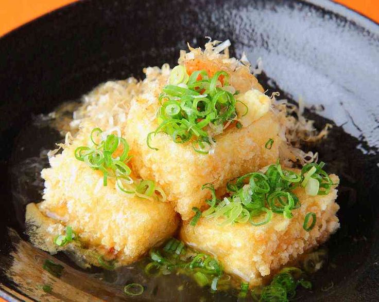 some food that is on top of a black plate with green onions and scallions