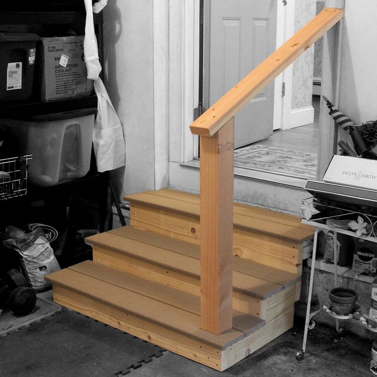 a black and white photo of a stair case in front of a door with a bag on the floor next to it