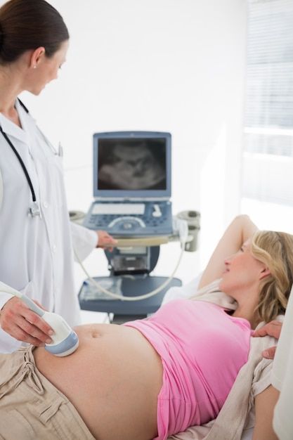 a pregnant woman laying in bed next to a doctor