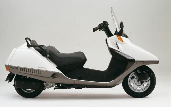 a white and black scooter parked on top of a white floor next to a wall