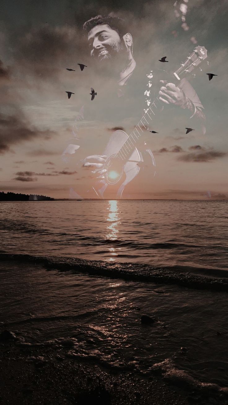 a man playing an electric guitar on the beach at sunset with birds flying over him