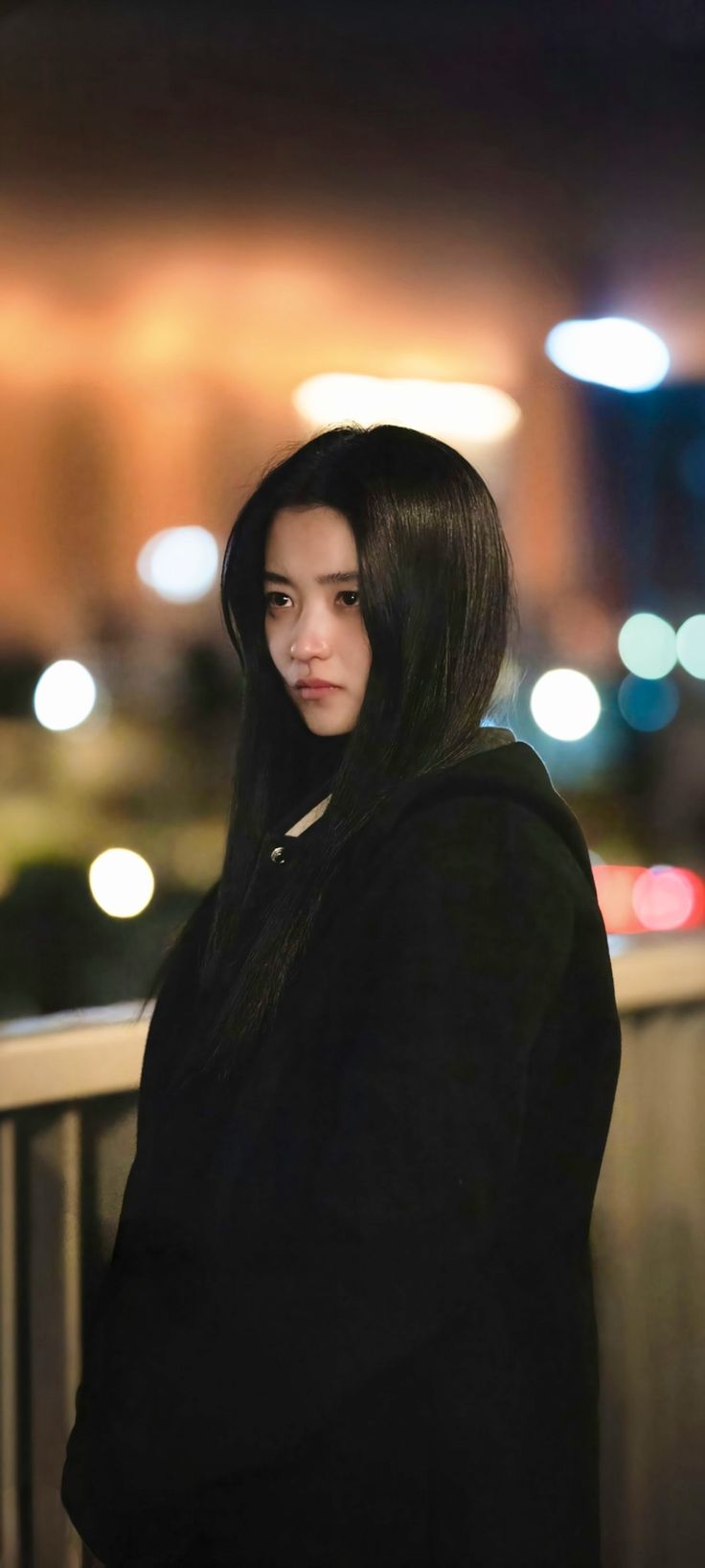 a woman with long black hair standing on a balcony