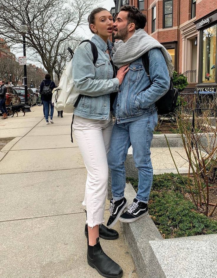 two people standing next to each other on a sidewalk