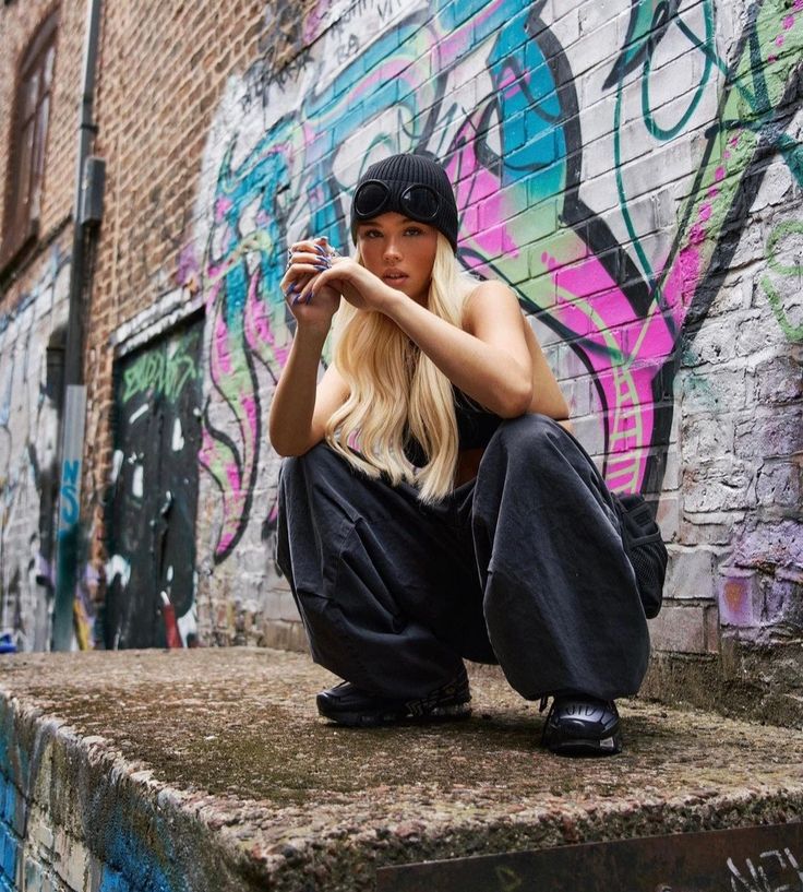 a woman sitting on top of a cement step next to a wall covered in graffiti