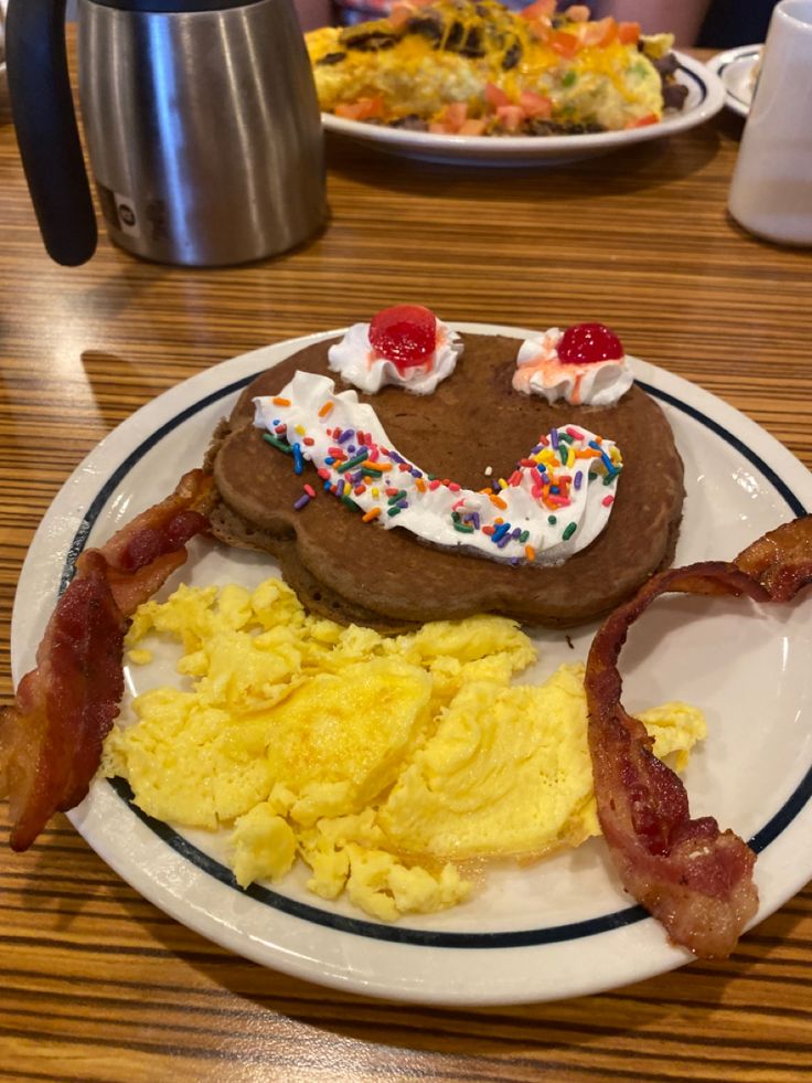 a breakfast plate with eggs, bacon, pancakes and hash browns