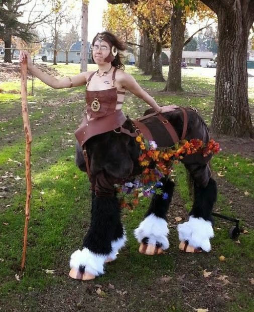 a woman dressed up as a horse with white legs and boots on, standing next to a tree