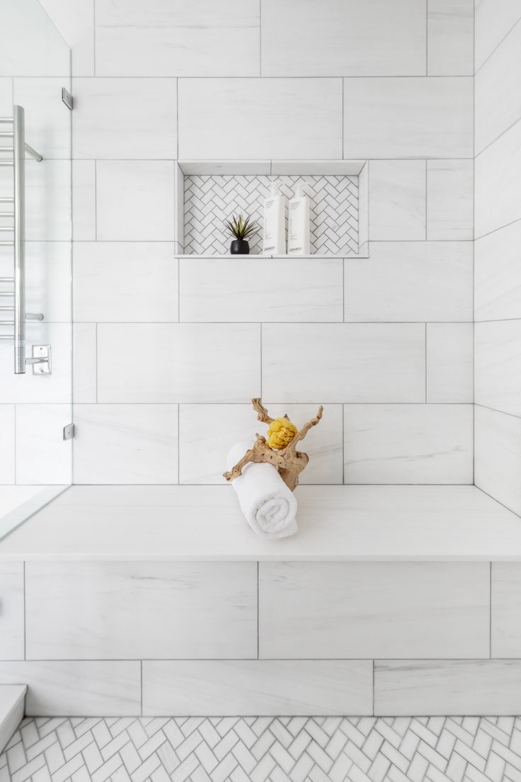 a white tiled bathroom with a towel rack