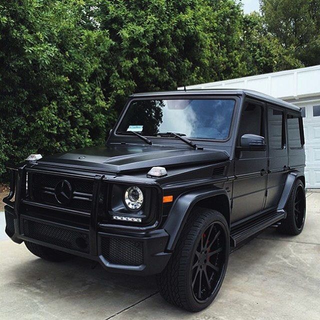 a black mercedes g - class parked in front of a house